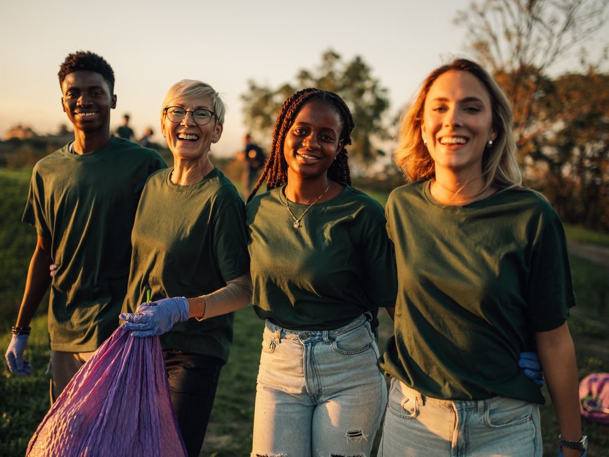 Cheerful volunteers cleaning up outdoors at sunset